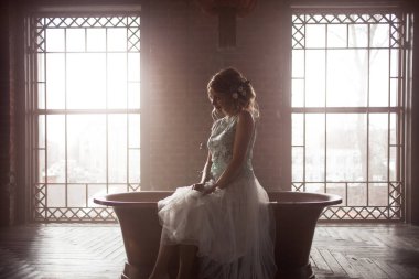 Genç gelin Giydir, siluet pencere arka plan üzerinde. ışıkta oturur.