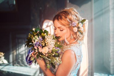 Buket çiçek ile gelinlik içinde genç güzel kadın. Düğün saç modeli, saç çiçekleri.