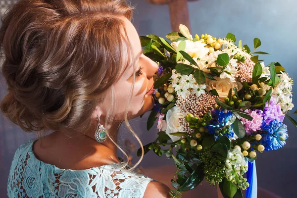 Mooie jongedame in bruiloft jurk met boeket bloemen. Bruiloft hairstyle, bloemen in haar. — Stockfoto