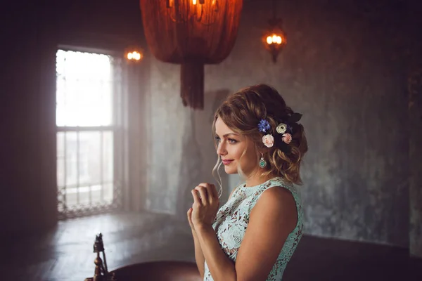 Jonge vrouw in jurk van kant en haar versierd met bloemen. — Stockfoto
