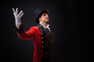 Sunum, gösteri başlıyor. Genç erkek şovmen, sunum veya Sahne Alanı'nda aktör. Adam kırmızı geceliğim ve silindir.