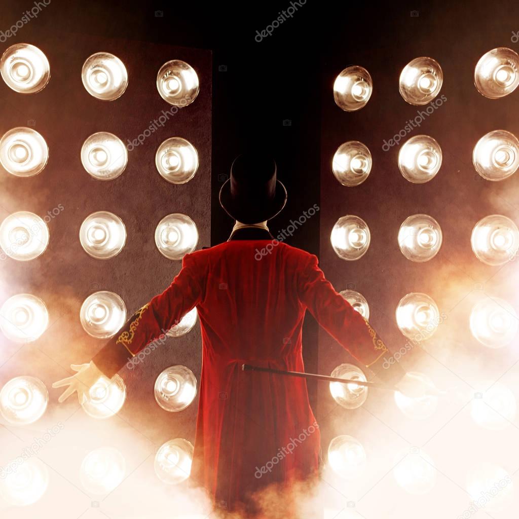 Showman Back, arms to sides. Young male entertainer, presenter or actor on stage. The guy in the red camisole