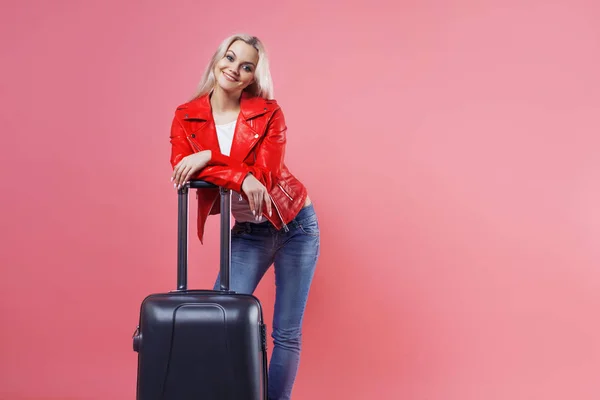 Ung vacker blond kvinna med resväska på rosa bakgrund. — Stockfoto