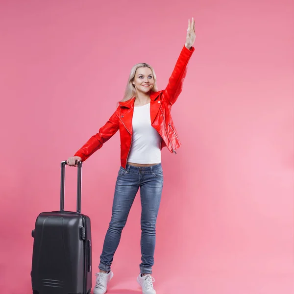 Snygg ung blond flicka på rosa bakgrund. Gå till flygplatsen, med resväska. Ringa en taxi — Stockfoto