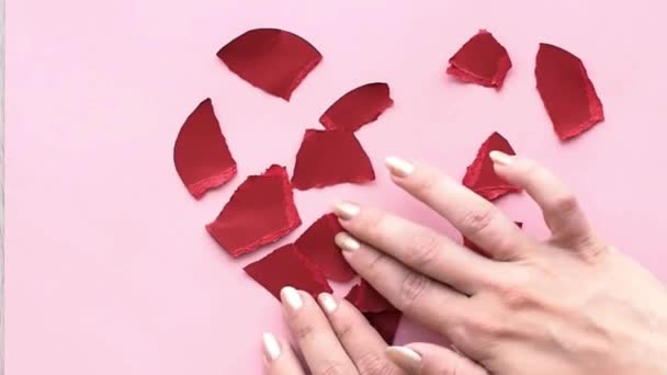 Gebrochenes Herz sammeln. die weibliche Hand sammelt das zerfetzte Herz — Stockvideo