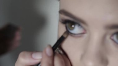 Makyaj sanatçısı göz dağılımı yapar. Genç kız profesyonel makyaj, siyah göz kalemi