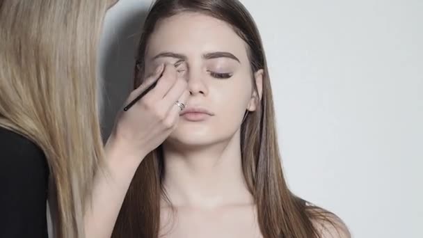 Maquillaje artista haciendo maquillaje para las cejas. Chica joven haciendo maquillaje profesional, la forma de la ceja — Vídeo de stock