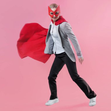 Genç çekici kadın kahraman. Kız bir takım elbise ve kahraman kırmızı pelerini ile bir maske.