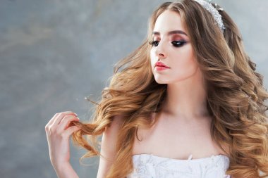 Lüks bukleler ile genç güzel gelin. Taç düğün saç modeli.