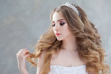 Lüks bukleler ile genç güzel gelin. Taç düğün saç modeli.