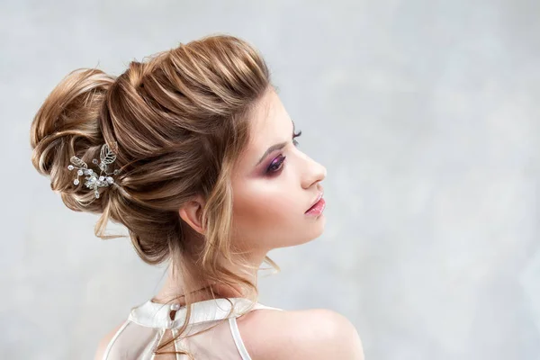 Joven novia hermosa con un peinado alto elegante. Peinado de boda con el accesorio en su cabello —  Fotos de Stock