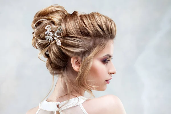 Joven novia hermosa con un peinado alto elegante. Peinado de boda con el accesorio en su cabello —  Fotos de Stock