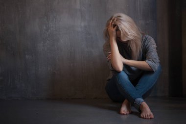 Duvara oturan üzgün genç kadın. Genç sarışın. Depresyon ve sorunları