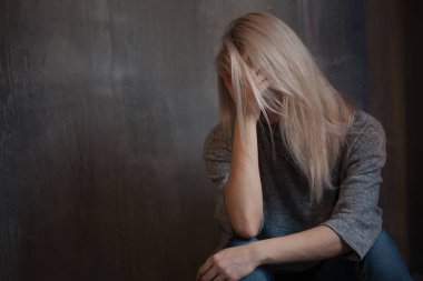 Duvara oturan üzgün genç kadın. Genç sarışın. Depresyon ve sorunları