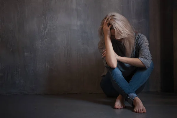 Una giovane donna triste seduta al muro. La giovane bionda. Depressione e problemi — Foto Stock