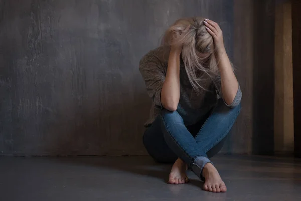 Una giovane donna triste seduta al muro. La giovane bionda. Depressione e problemi — Foto Stock