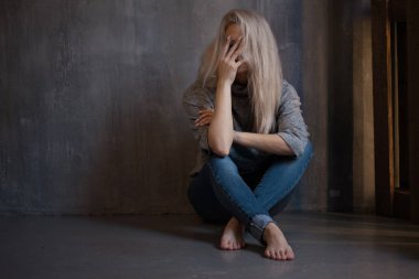 Duvara oturan üzgün genç kadın. Genç sarışın. Depresyon ve sorunları