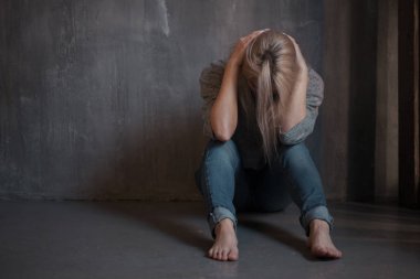 Duvara oturan üzgün genç kadın. Genç sarışın. Depresyon ve sorunları