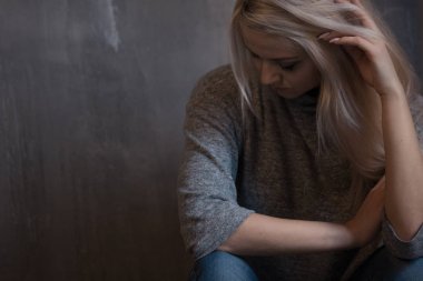 Duvara oturan üzgün genç kadın. Genç sarışın. Depresyon ve sorunları