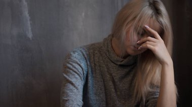 Duvara oturan üzgün genç kadın. Genç sarışın. Depresyon ve sorunları