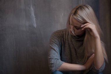 Duvara oturan üzgün genç kadın. Genç sarışın. Depresyon ve sorunları