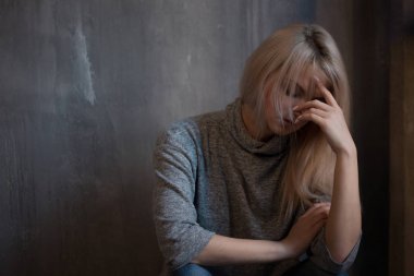 Duvara oturan üzgün genç kadın. Genç sarışın. Depresyon ve sorunları