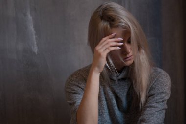 Duvara oturan üzgün genç kadın. Genç sarışın. Depresyon ve sorunları