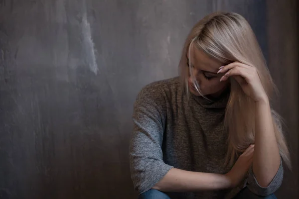 Triest jonge vrouw zit op de muur. De jonge blonde. Depressie en problemen — Stockfoto