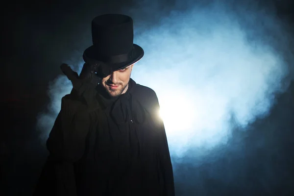 Adam siyah silindir şapka ve pelerin. Şeytani görüntü. Sihirbaz illüzyonist — Stok fotoğraf