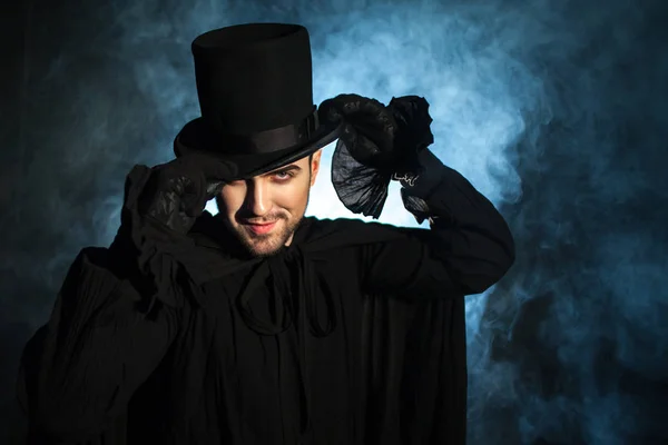 Un hombre con un sombrero negro y una capa. Imagen demoníaca. Ilusionista mago — Foto de Stock