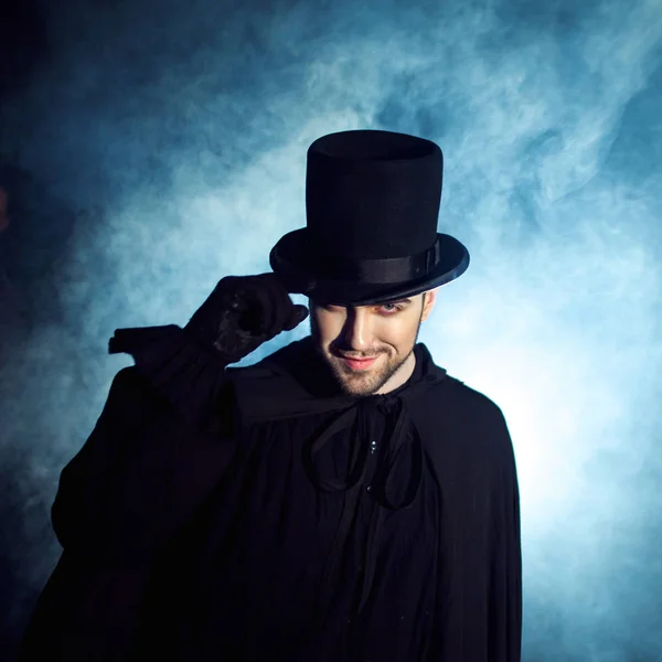 Un hombre con un sombrero negro y una capa. Imagen demoníaca. Ilusionista mago — Foto de Stock