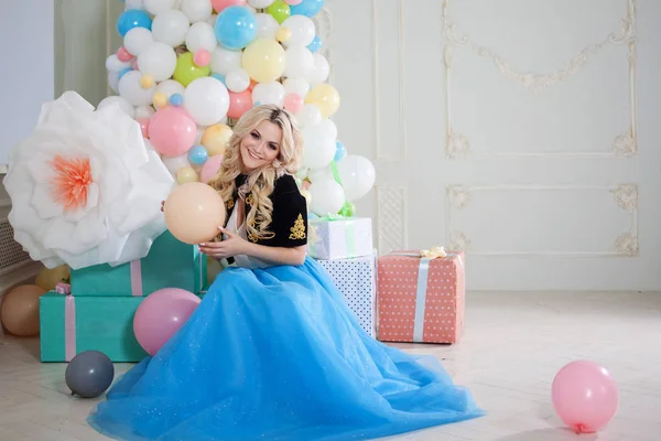 Leuke en mooie blonde in een prachtig interieur. Charmante jongedame in een bochtige blauwe rok. — Stockfoto