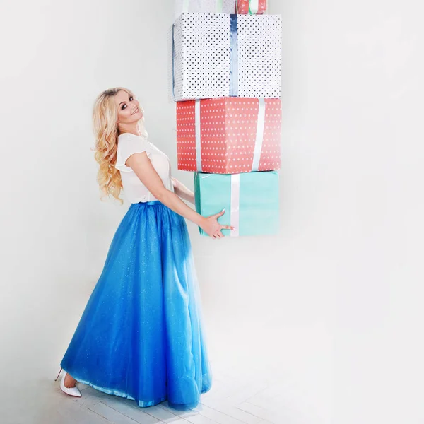 Забавная и красивая блондинка с кучей больших подарочных коробок. Очаровательная девушка в пышной голубой юбке . — стоковое фото