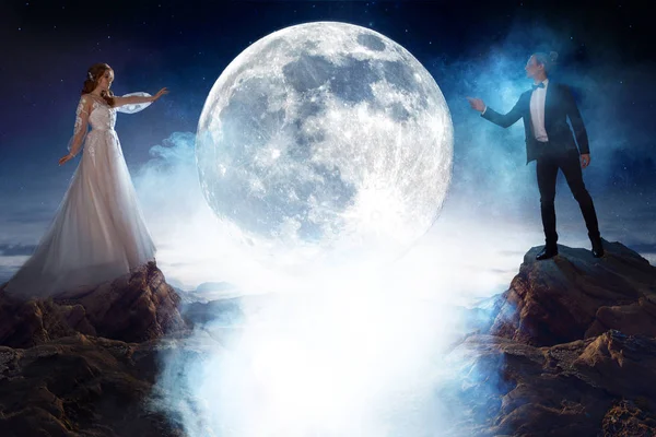 Таинственная и романтическая встреча, невеста и жених под луной. Мужчина и женщина дергают друг друга за руки. Смешанные медиа — стоковое фото