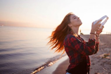 Mutlu çekici Kızıl saçlı kız müzik yürüyüşte keyif alıyor. Güzel genç kadın gömlek kulaklıklar, yumuşak odak kullanır