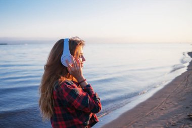 Mutlu çekici Kızıl saçlı kız yolda favori müzik keyfi. Güzel genç kadın gömlek kulaklık kullanır