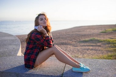 Doğa ve iyi hava zevk Rıhtımlar üzerinde oturan güzel genç Kızıl saçlı kadın. Kırmızı ekose gömlekli kız