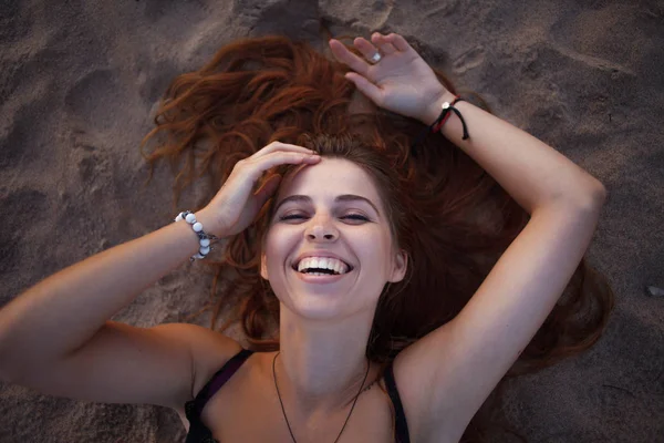 Happy attractive young woman lying on sand, closeup portrait — Stock Photo, Image