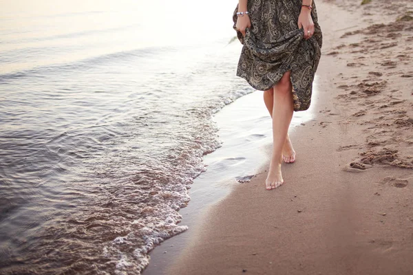 Young woman walking barefoot on surf line, Legs and skirt close up — Stock Photo, Image