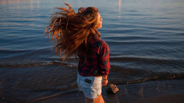 Cute cheerful young woman portrait at sunset. Attractive girl in shirt and shorts, hair in wind — Stock Photo, Image