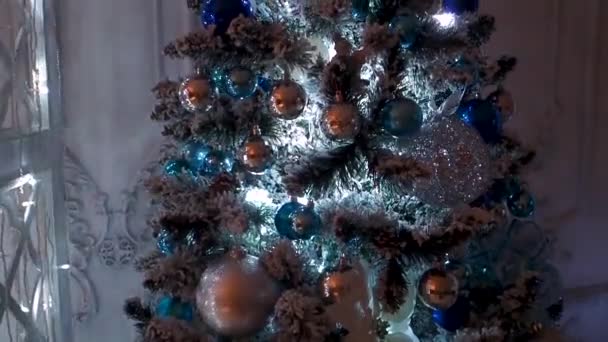 Elegante árbol de Navidad, un montón de juguetes y guirnalda intermitente, panorámica de abajo hacia arriba . — Vídeos de Stock