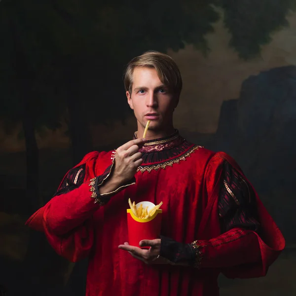Pohledný muž v královském červeném kabátci jí hranolky — Stock fotografie