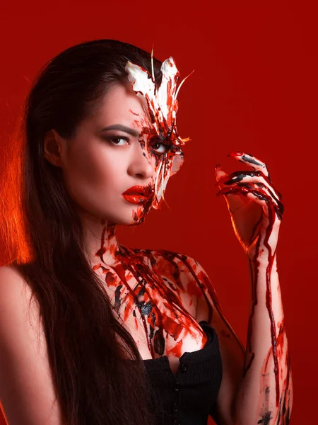 Lily Sangue, olhar assustador e sexy Halloween. Menina morena bonita no fundo vermelho . — Fotografia de Stock