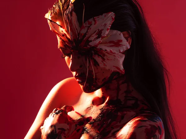 Lily Sangue, olhar assustador e sexy Halloween. Menina morena bonita no fundo vermelho . — Fotografia de Stock