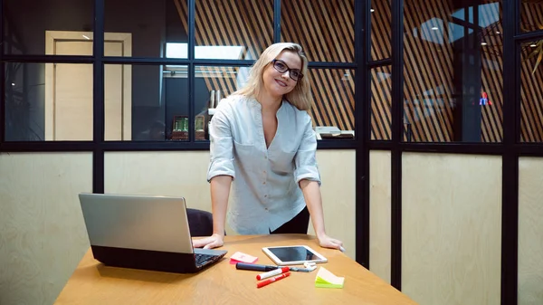 Młoda bizneswoman w swoim biurze. Praca w biurze, profesjonalna dziewczyna stoi przy stole z laptopem, — Zdjęcie stockowe
