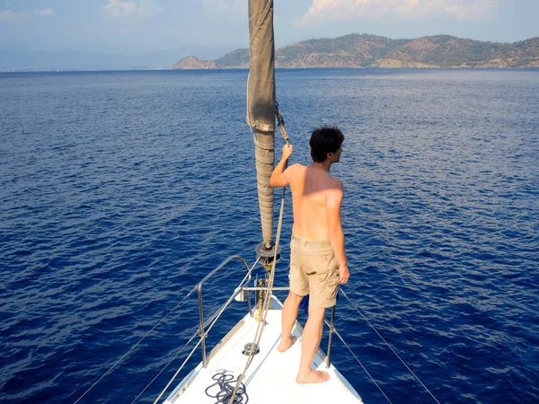 look beyond the horizon. man in shorts stands on the deck near the sail, sailing and yachting, concept.