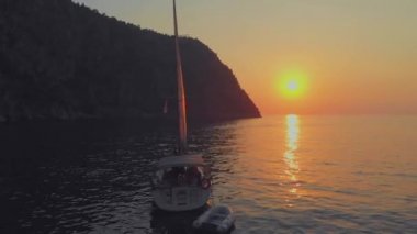 Yat, güzel beyaz bir yat kıyıdan ayrılıyor. Pembe gün batımı