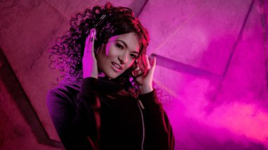 Büyük kulaklıklı güzel, kıvırcık kadın gülümser, müzik dinler, şarkı söyler, dans eder, zıplar, gözlerini kapatır..