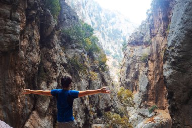 Doğayla bütünleşmiş bir gezgin, bir kayanın üzerinde genç bir adam oturuyor.