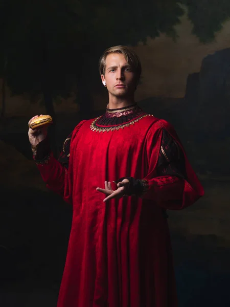 Красивый мужчина в красном королевском дублете ест фаст-фуд — стоковое фото